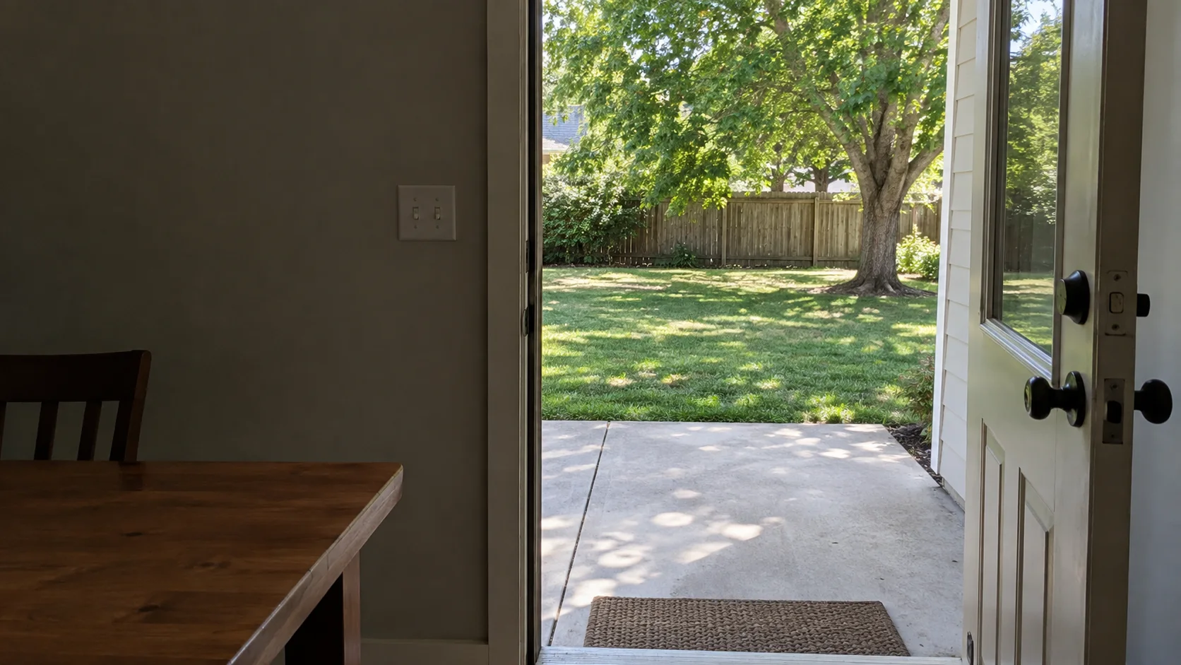 An open door leading from a quiet room into a sunlit yard